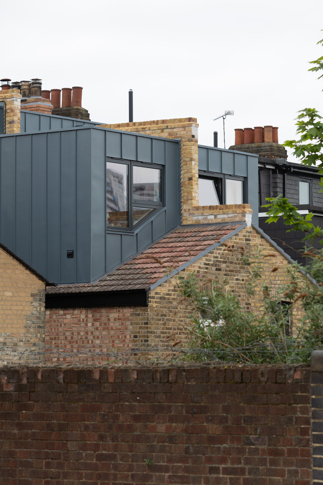 Rear exterior showing completed zinc-clad loft extension at Keogh Road Stratford
