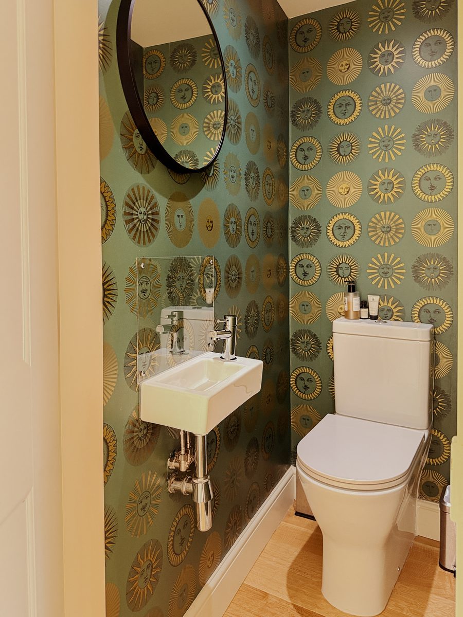 Limehouse Cottage: downstairs cloakroom with patterned wallpaper and round mirror