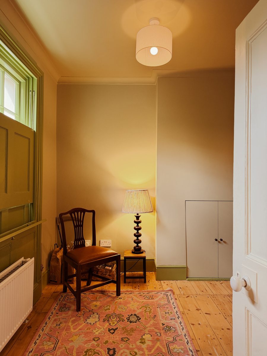 Limehouse Cottage: hallway with the restored original floorboards, rug and side chair